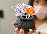 Candy cauldron with lollipops shaped like a pumpkin, witch hat, ghost, spider and cobweb made by a kid in our Halloween events and activities for kids.